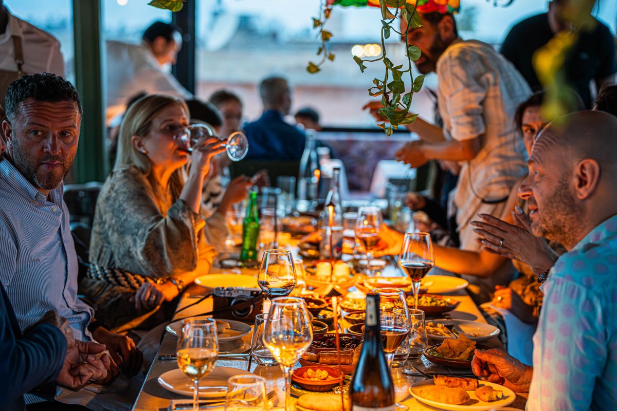A group dining at a long table on a terrace at sunset