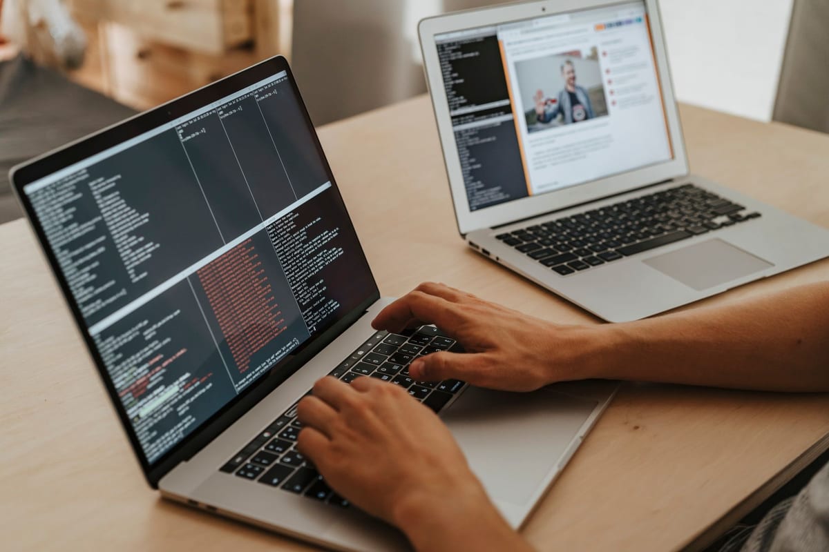 Dos portàtils sobre una taula amb el codi d'una pàgina web a la pantalla
