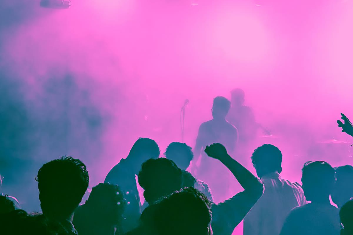 Crowd with hands in the air under coloured lights